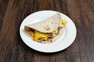 A folded flour tortilla taco filled with scrambled egg and refried beans.
