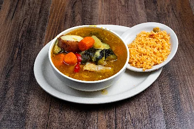 A bowl of caldo de res: beef broth with potato, carrot, squash and cabbage, with a side of Mexican rice.
