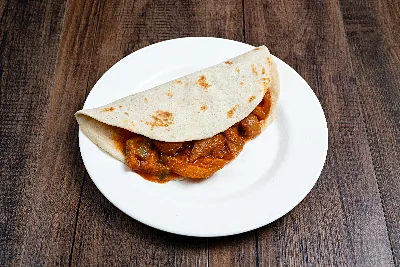 A folded flour tortilla taco filled with chicharrón simmered in red chile sauce.