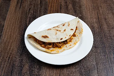 A folded flour tortilla taco filled with chorizo scrambled into egg.