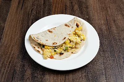 A folded flour tortilla taco filled with egg scrambled with tomato, onion and green chile.