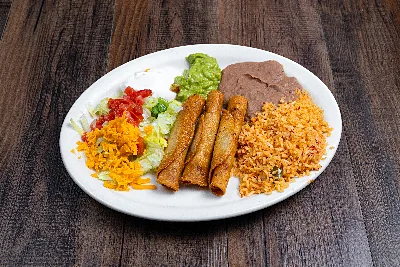 Three crisp rolled flautas on an oval plate with guacamole, Mexican rice, refried beans and shredded salad.