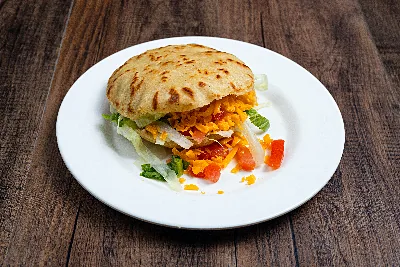A thick masa gordita split and filled with shredded meat, lettuce, tomato and cheese.