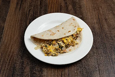 A folded flour tortilla taco filled with machacado shredded beef scrambled with egg, onion and cilantro.